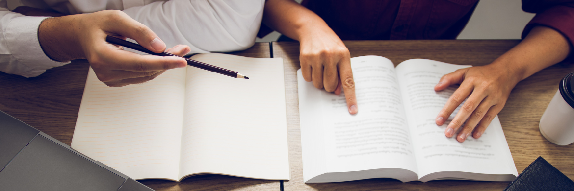 Two people reading at a desk. 