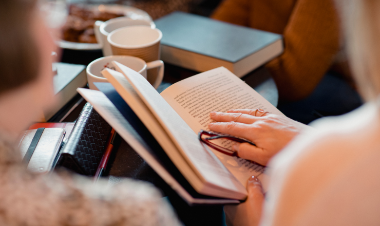 Person holding book and reading glasses