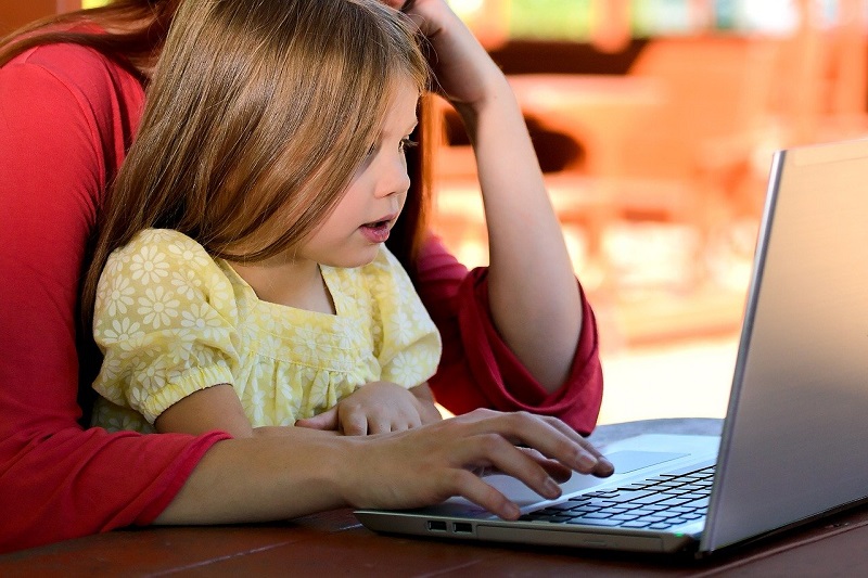 Picture of little girl on lady's lap looking at a laptop computer