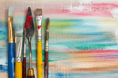 Graphic of used paintbrushes on a background of horizontal bright paint brushstrokes over wood