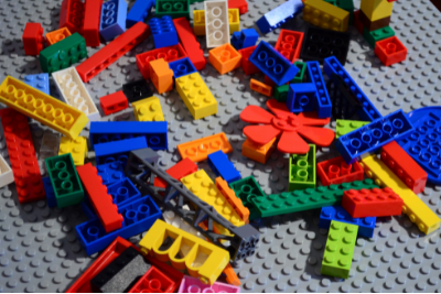 Multicolored and shaped Lego bricks spilled over a gray base plate.