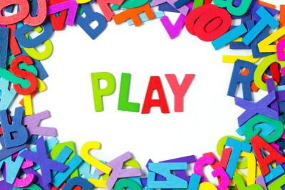 Graphic of the word PLAY spelled out in multicolored letters on a white background with random layers of multicolored letters of the alphabet around image border.