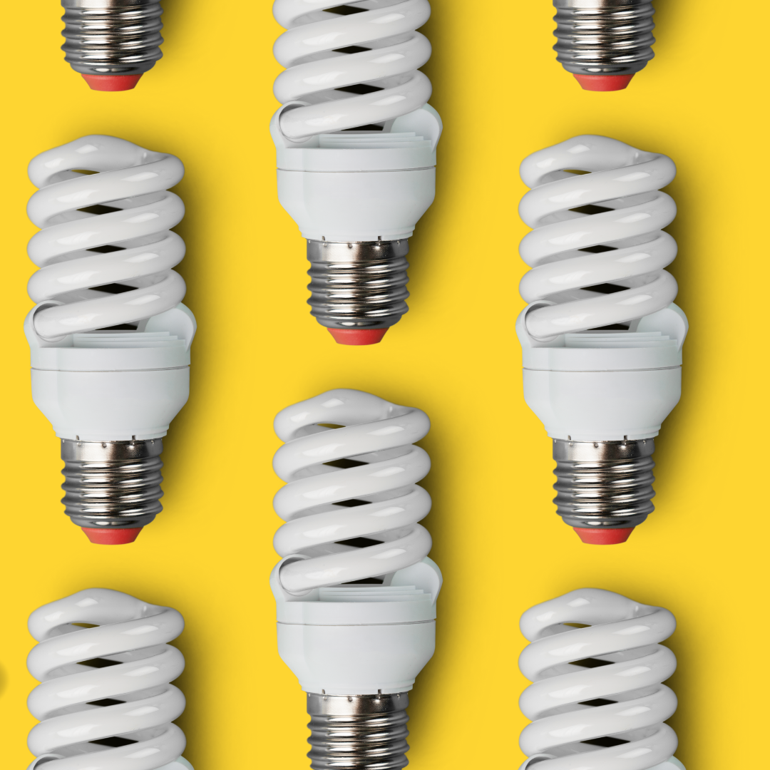 Energy saving spiral lightbulbs place in a pattern on top of a bright yellow background.