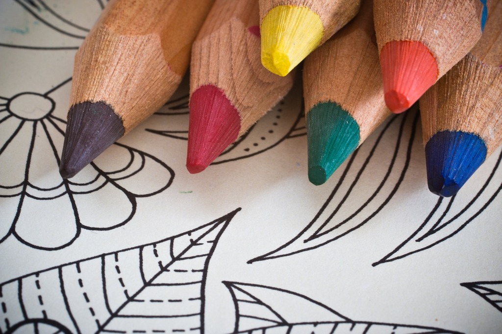 six sharpened colored pencils sit on top of a blank coloring page