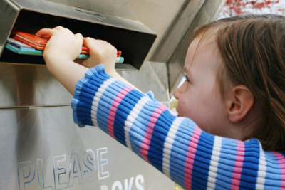 Small child return books to library book drop