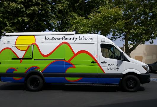 photo of the Ventura County Mobile Library-bookmobile; exterior is wrapped with the Library logo of hills and ocean