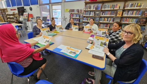 group of people sitting at a table holding a story