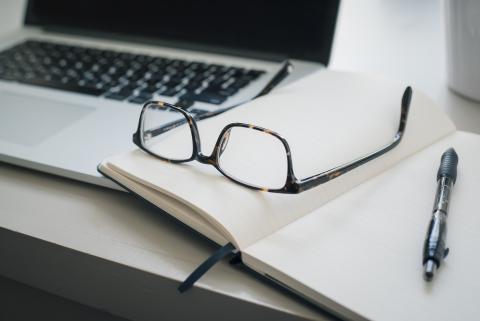 glasses and pen on a book resting atop a keyboard - photo by Trent Erwin on Unsplash