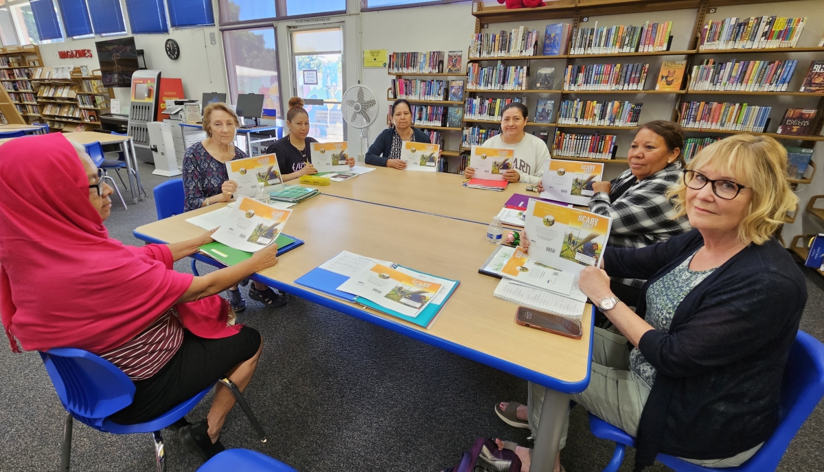 group of people sitting at a table holding a story