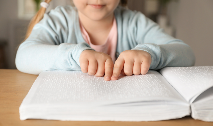 small child reading braille book