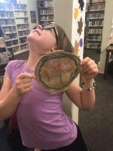 Child showing off her embroidery in library