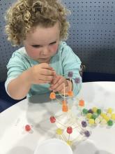 Picture of little girl making a structure from gumdrops and toothpicks