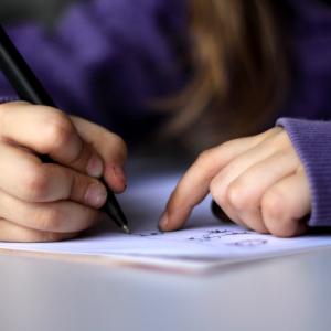 young person writing, purple shirt