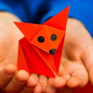 A child's hands holding a red fox made out of origami