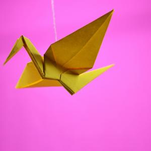 yellow crane origami against a pink background
